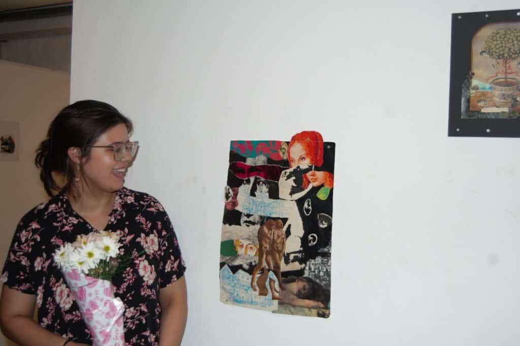Una mujer sosteniendo flores y mirando una pared con imágenes.