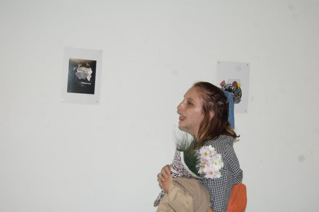 Una mujer parada frente a una pared con imágenes.
